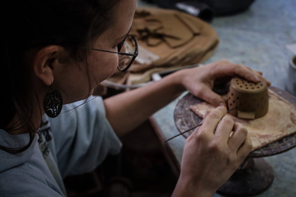 A dedicated woman focuses on crafting a unique pottery piece in a Prague workshop.