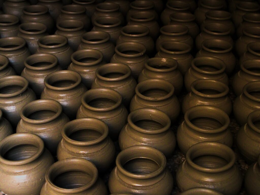 Close-up of numerous handcrafted clay pots arranged in rows, showcasing pottery texture and detail.